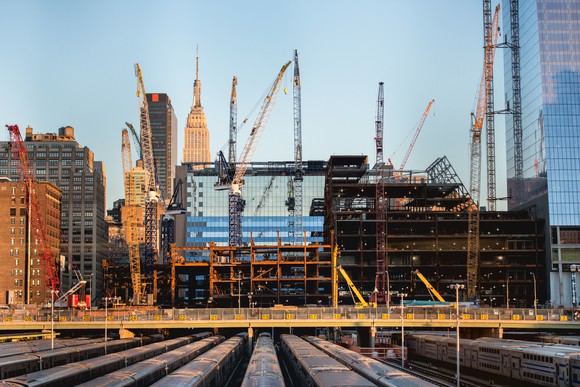 Several construction machinery like cranes at work on a construction site.