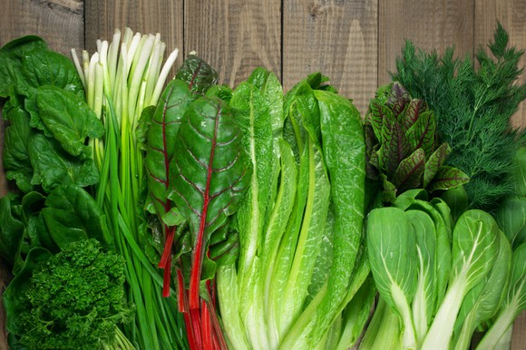 Leafy green vegetables on rustic wood table.