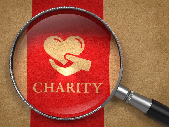 Red ribbon with charity and a hand holding a heart printed on it.