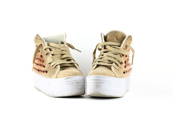 A pair of golden sneakers in a white room.