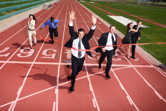 Business people running to a finish line on a running track.