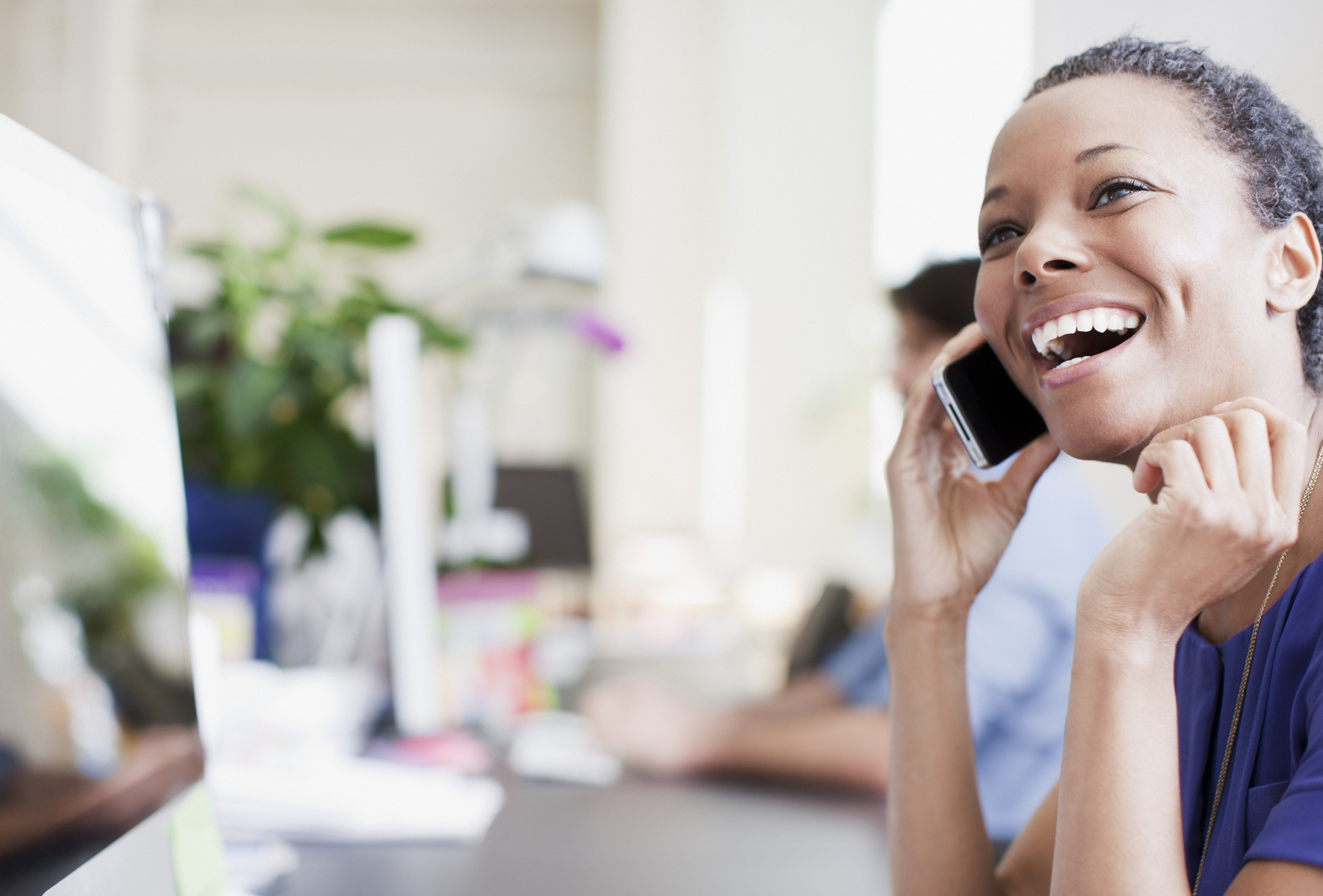A woman smiling and talking on a smartphone.