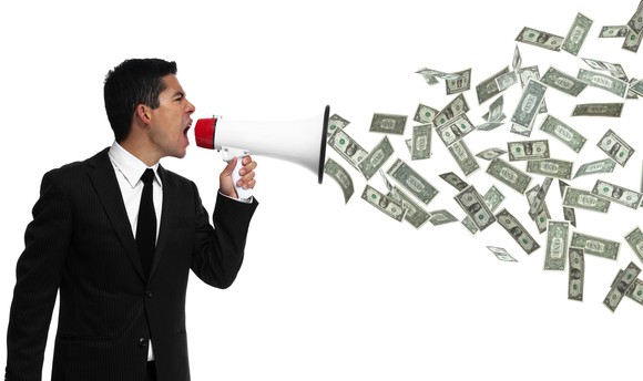 Businessman yelling into megaphone with money emerging