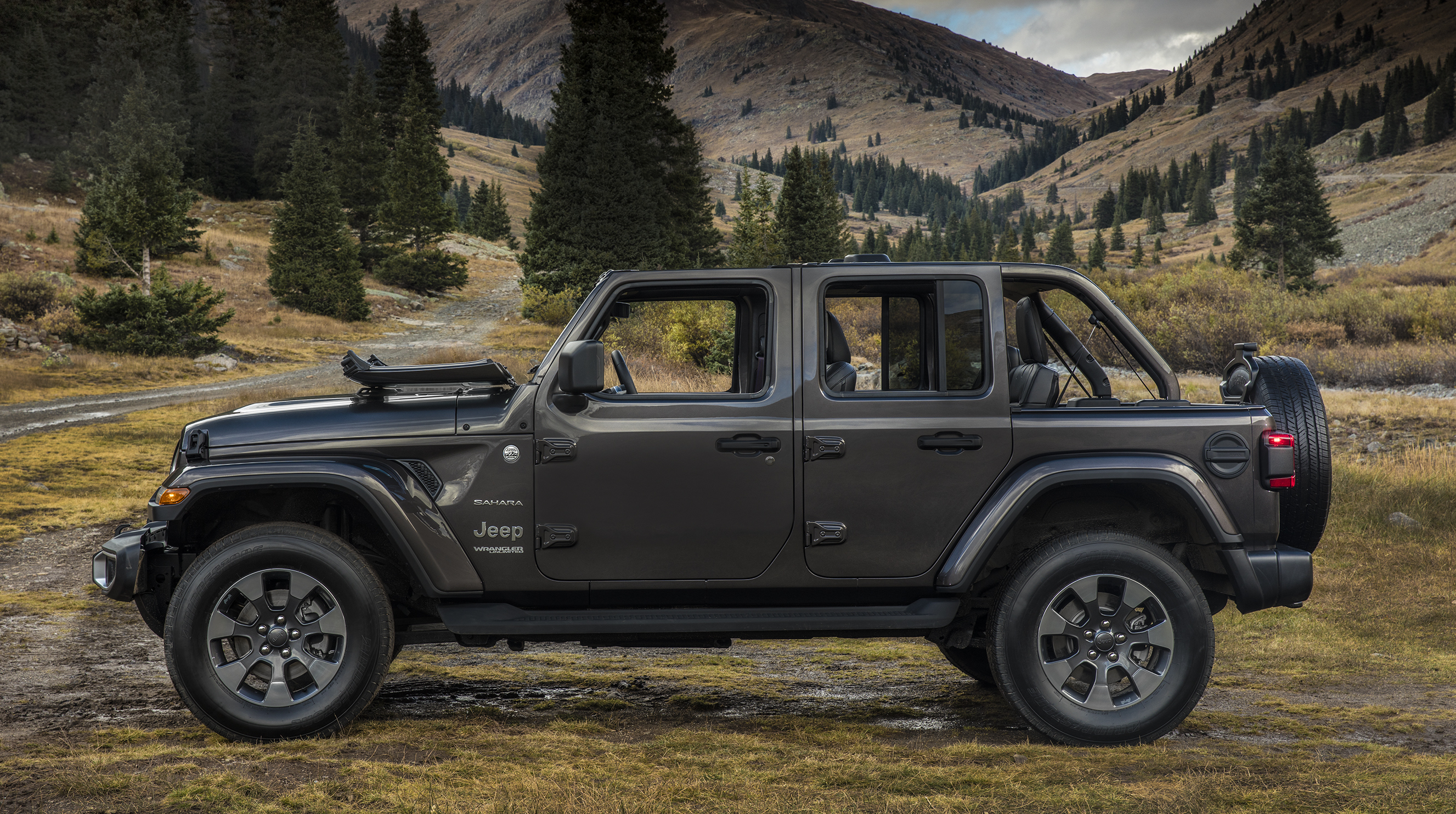 A green 2018 Jeep Wrangler Unlimited Sahara near a mountain road.