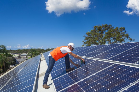 A worker installing solar panels on a rooftop.