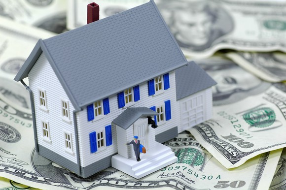 replica of house, sitting on US currency bills