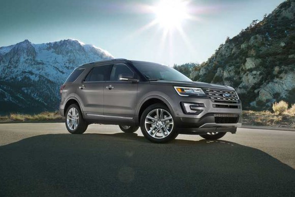 A 2017 Ford Explorer parked in front of mountains with the sun shining.
