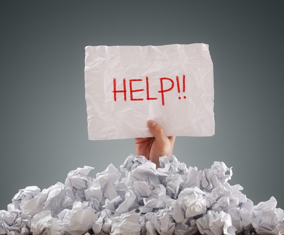 Person buried in paper holding Help sign