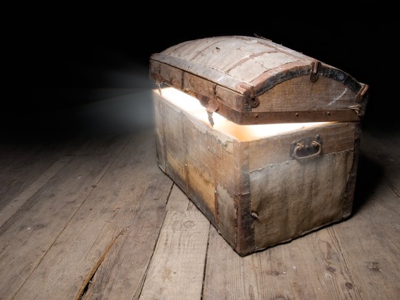 A slightly opened treasure chest sitting on an old floor.