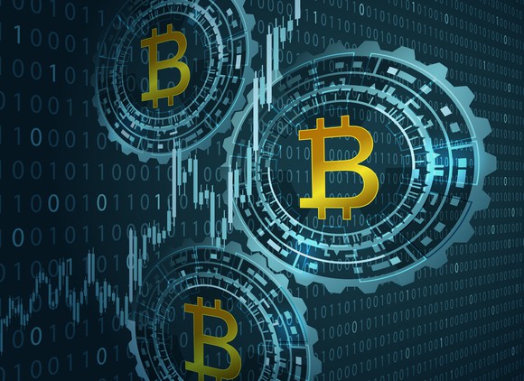 Three bitcoin logos on a background of binary code.