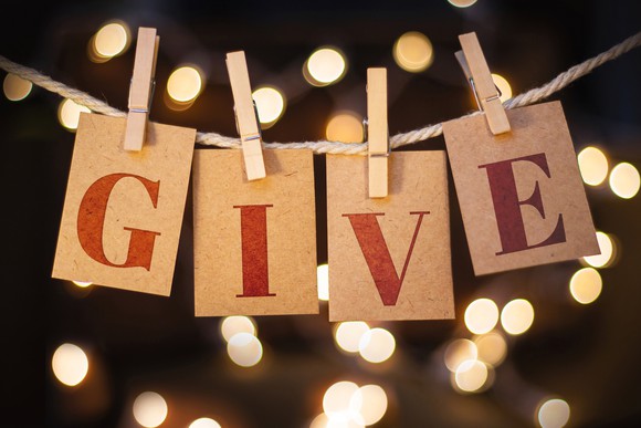 The letters G-I-V-E hanging from a clothesline on gold paper