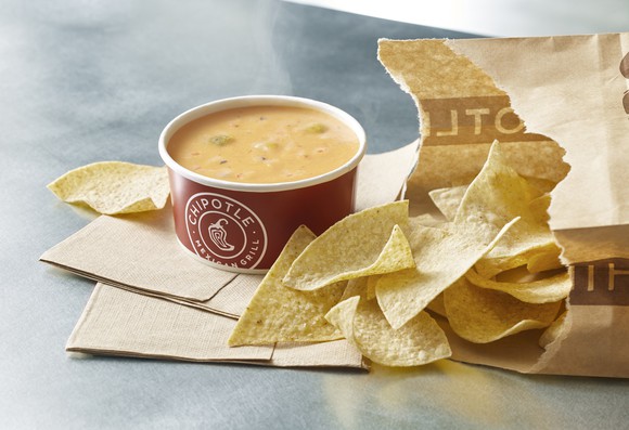 Chipotle Mexican Grill cup of queso with chips spilling out of a bag
