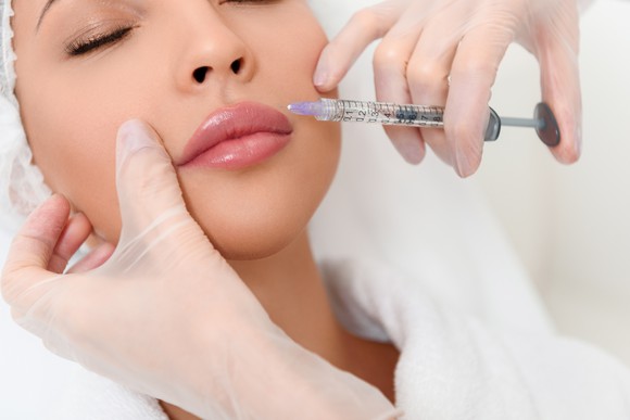 Woman getting injected by needle in face
