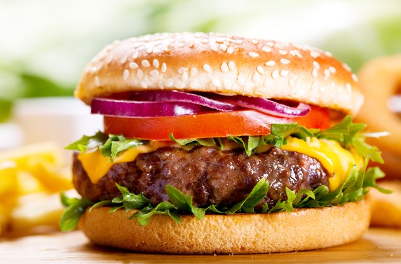 Hamburger on a bun with lettuce, tomato, onion, and cheese.