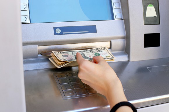 A hand pulling money out of an ATM.