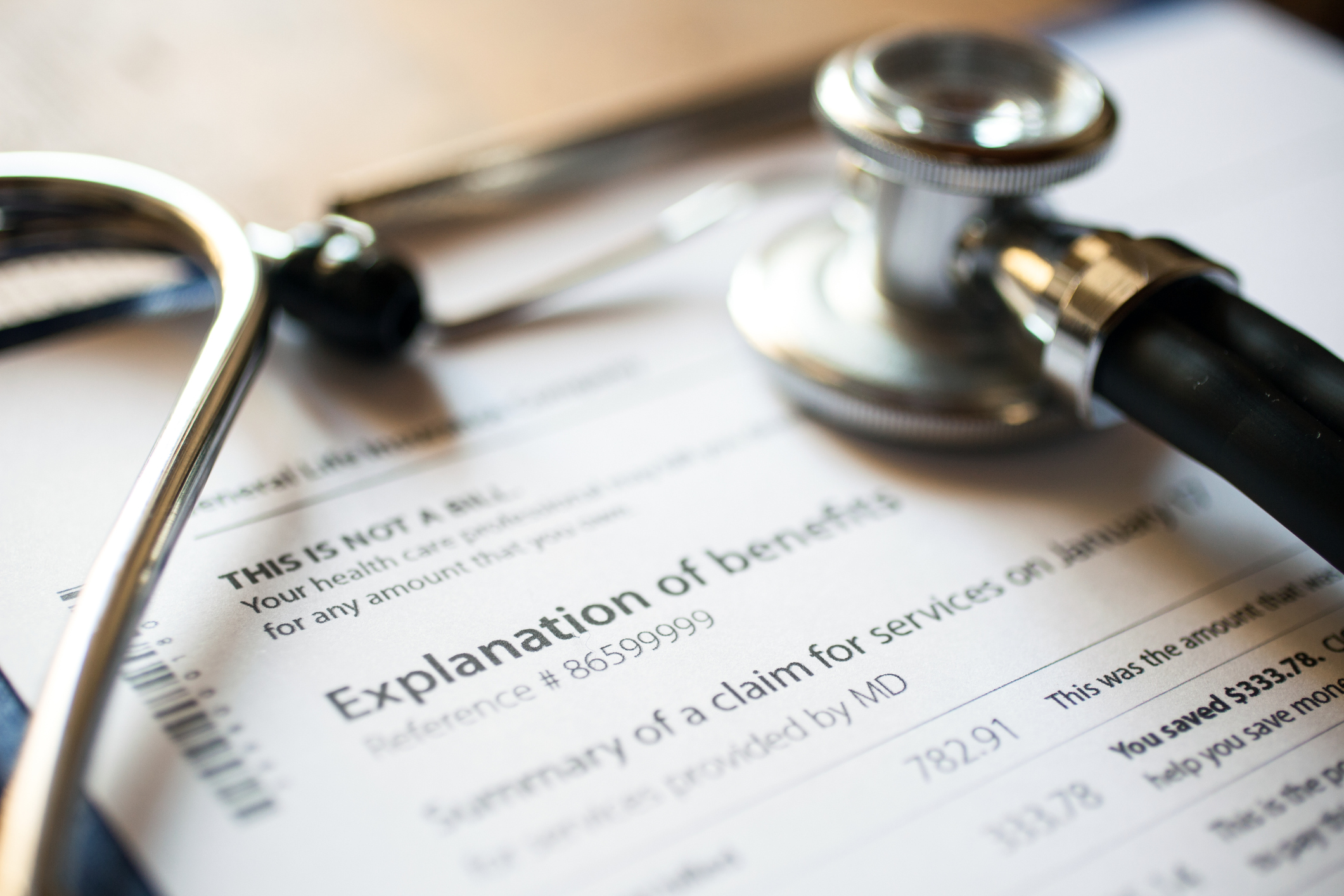 A stethoscope rests on a piece of paper that reads explanation of benefits.