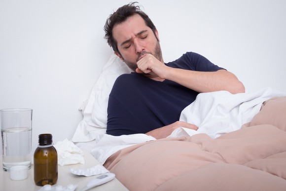Man sick in bed, coughing