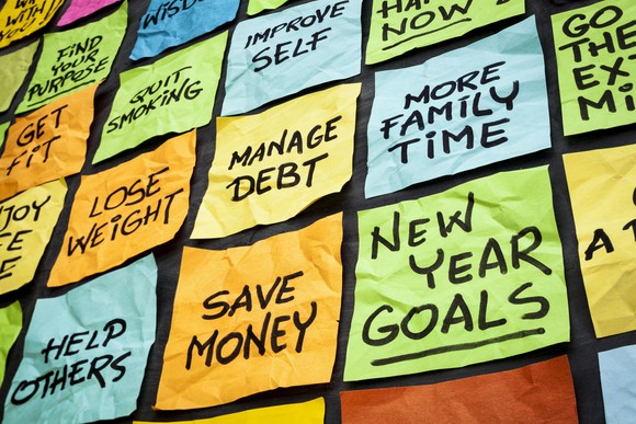 colorful sticky notes on a blackboard with goals on each such as save money manage debt more family time