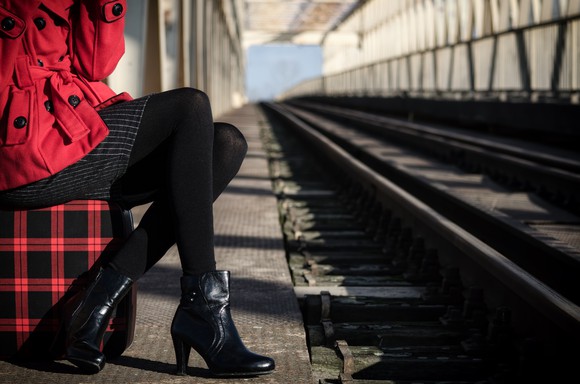 A well-dressed is seated in a train station.