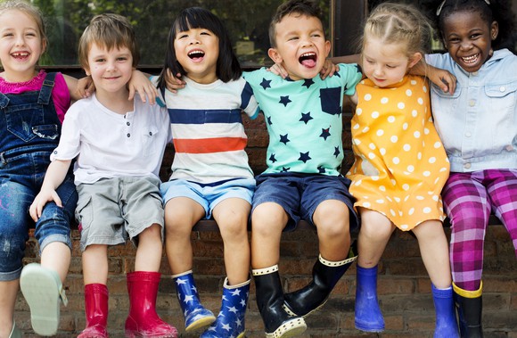 A row of children sitting on a bench and laughing