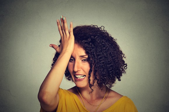 Woman slapping her forehead with regret Woman slapping her forehead with regret