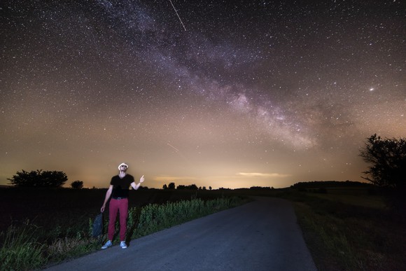 Hitchhiker pointing to Milky Way