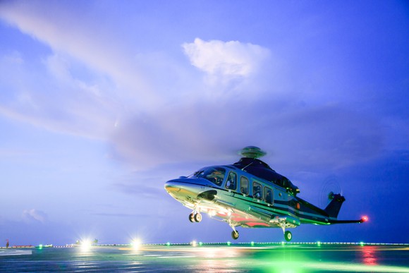 Helicopter landing on a heli pad at dusk.