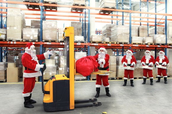 A group of Santas is shiw in a shipping warehouse.