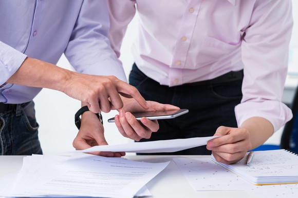 Two men looking over numbers before a presentation.