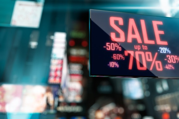 Sale sign showing various percents off with cityscape in the background