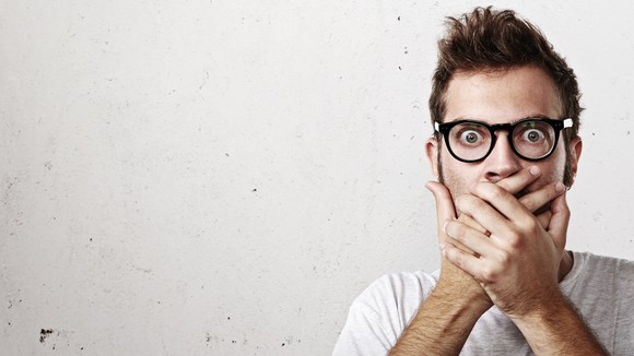 young man looking shocked, with his hands over his mouth
