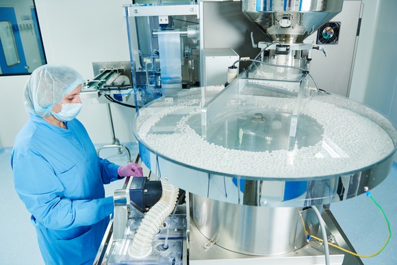 Pharmaceutical worker operates tablet blister packaging machine