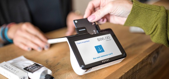 A person using their credit card in the POYNT payments terminal.