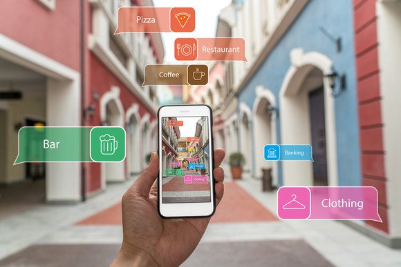 Looking at a smart phone whilst walking down a narrow street. The buildings are tagged with augmented reality labels like "coffee" and "bar", telling the user what they are.