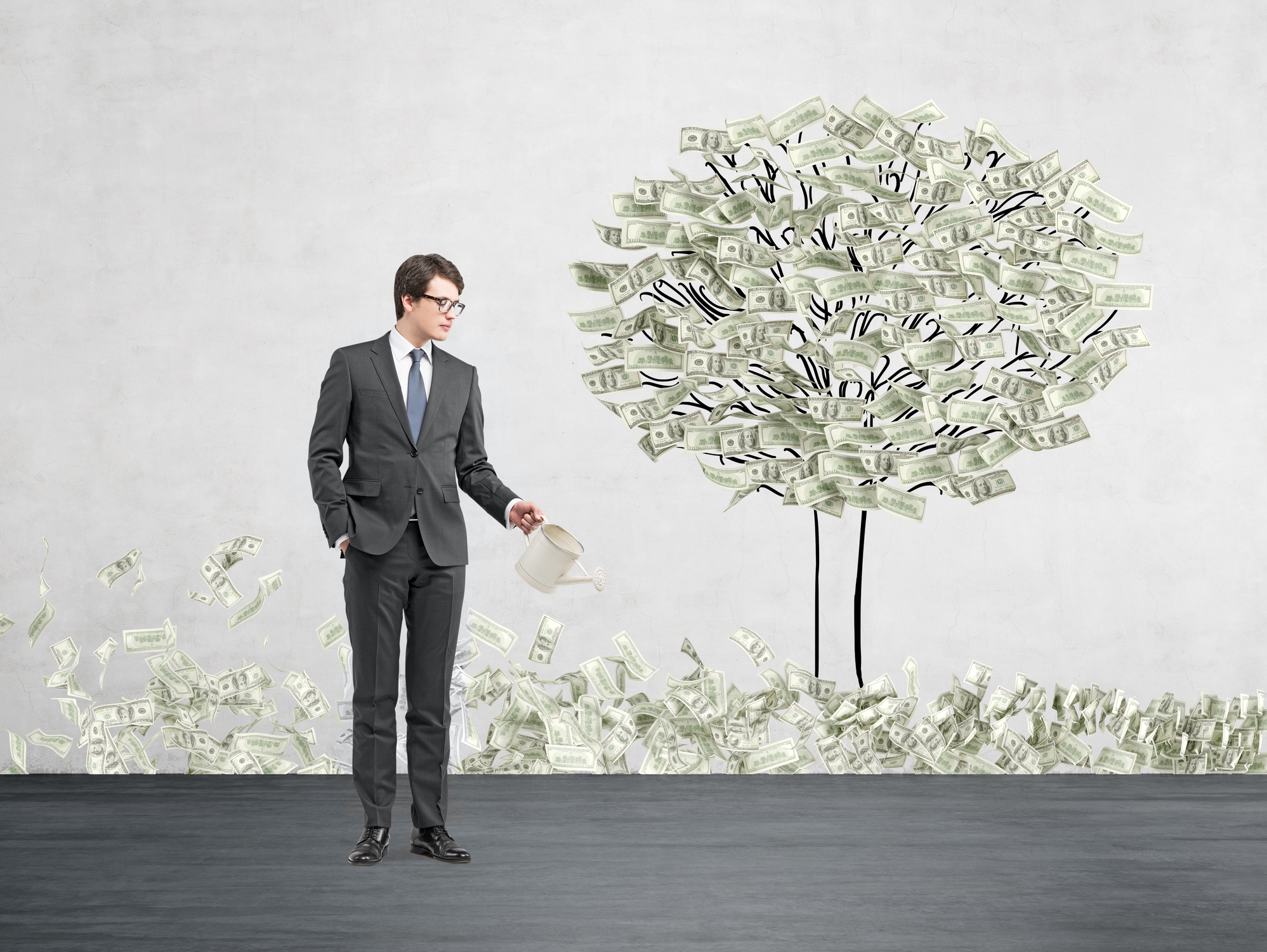 A businessman waters a "money tree".