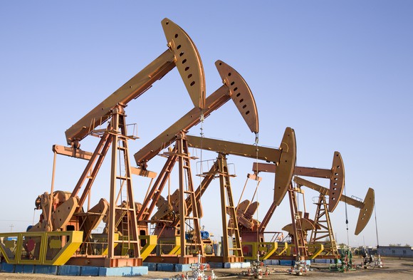 A row of pump-style oil wells in a desert landscape