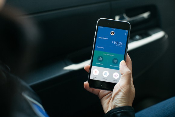 A person holding a smartphone with the PayPal app opened.