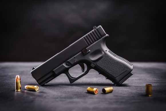 Handgun on a table with assortment of bullets.