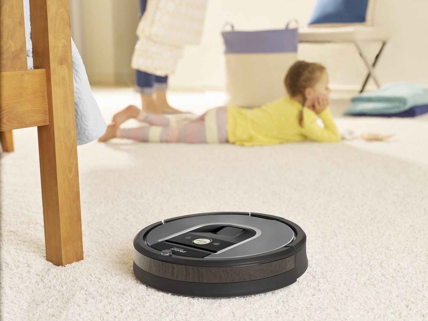 Roomba cleaning carpet with small child relaxing in the background