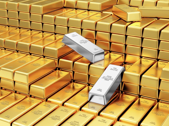 Two silver bars amid stacks of gold bars.