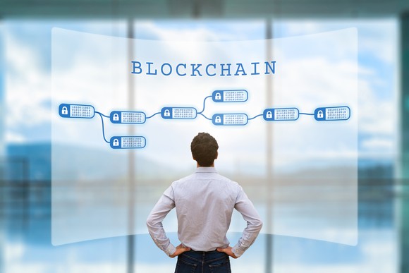 A man looking at an encrypted blockchain on a large digital screen.