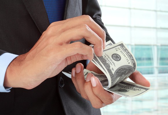 Man in suit counting hundred dollar bills