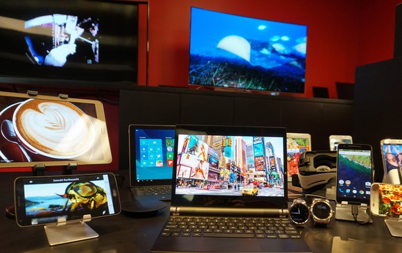 TVs, computers, phones, tablets, and watches displayed on a table, all featuring Universal Display's OLED screen technology.