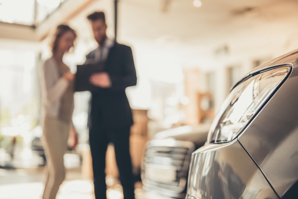 A car dealer shows a customer a car.