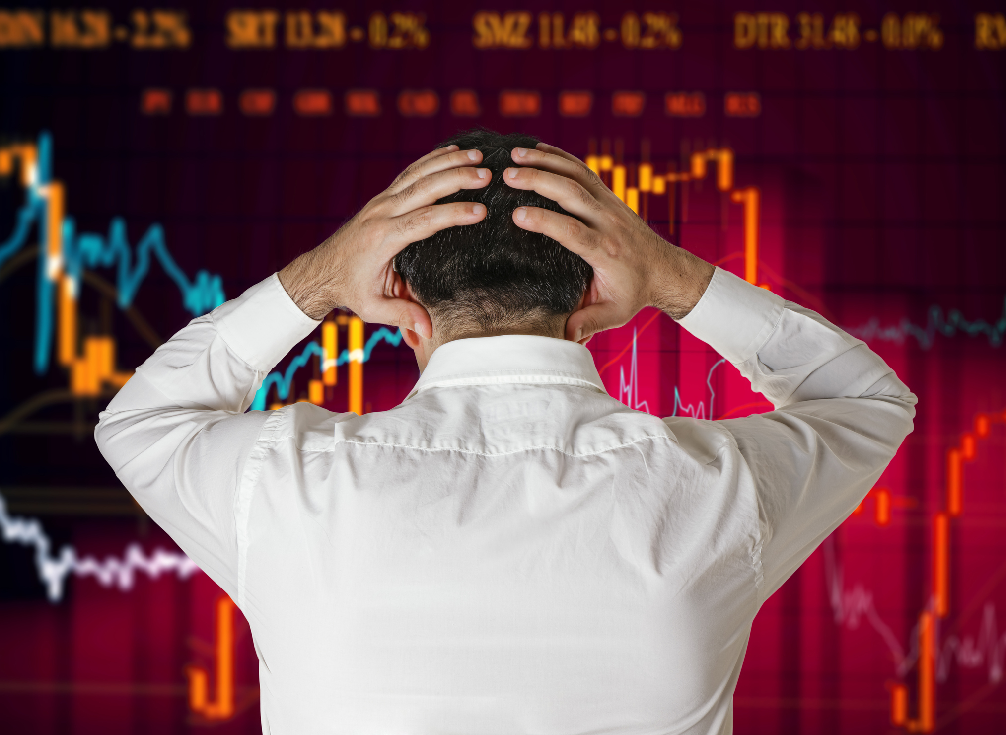 Man looking at stock market charts with hands on head.