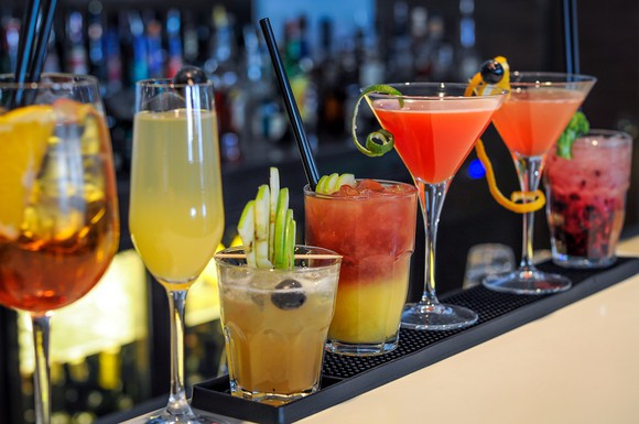 Various drinks lined up at a bar.