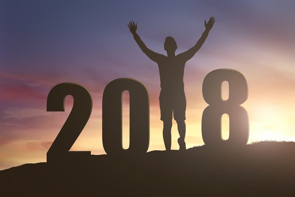 Silhouette of 2018 on hill with man holding arms up in place of the 1