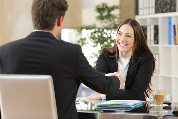 Smiling businesswoman shakes hands with businessman.
