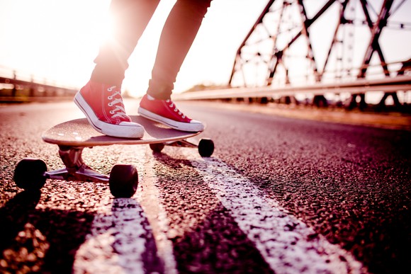 A person in athletic shoes riding a longboard