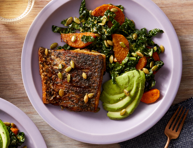 Mexican-spiced barramundi (fish) with kale, sweet potato, and avocado salad on white plate.